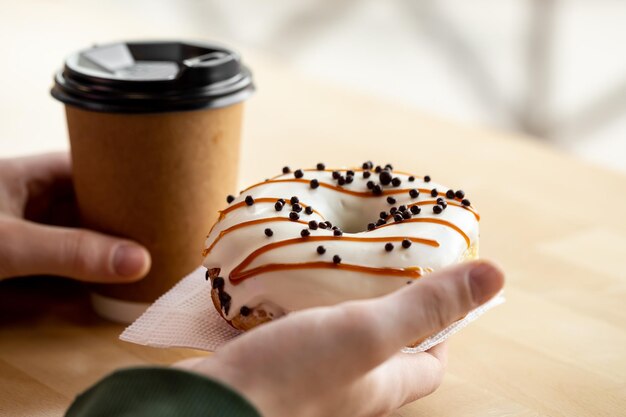 Smakelijke donut en koffie in mannelijke handen close-up