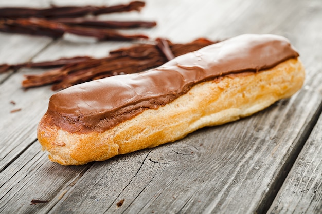 Smakelijke eclair met chocoladeroom op oude houten tafel