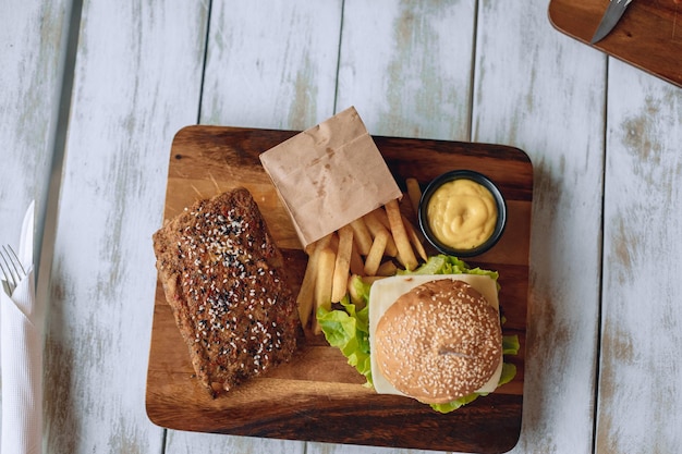 Smakelijke fastfoodlunch op een houten standaard met frietjes en saus.