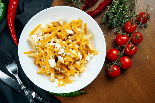 Foto smakelijke frietjes met cheddarkaas in een witte kom op een houten tafel in een compositie met ingrediënten. frietjes met beleg