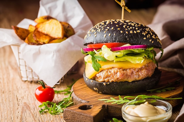 Smakelijke gegrilde klassieke zwarte rundvleesburger met sla en mayonaisesaus op een rustieke houten tafel