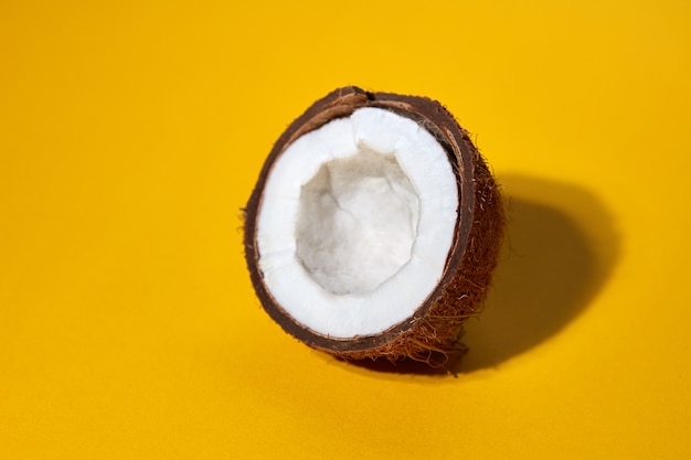 Smakelijke gehalveerde kokosnoot met reflectie op een gele achtergrond. Voedselconcept met kopieerruimte