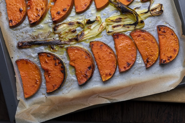 Smakelijke geroosterde pompoenplakken op bakseldienblad. Met ui.