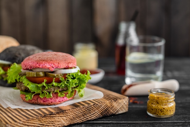 Foto smakelijke hamburger met vlees en groenten tegen een donkere achtergrond. fast food. het kan als achtergrond worden gebruikt