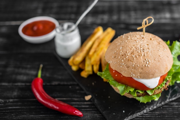 Smakelijke hamburger met vlees en groenten tegen een donkere achtergrond. fast food. het kan als achtergrond worden gebruikt