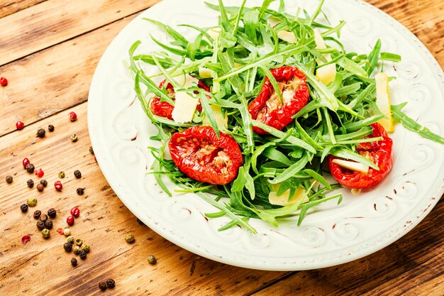 Smakelijke Italiaanse salade met rucola, zongedroogde tomaten en kaas.Zomersalade