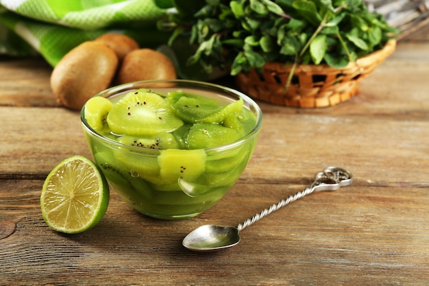 Smakelijke kiwi-jam in glazen kom op houten oppervlak