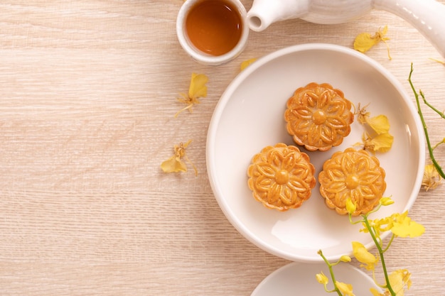 Smakelijke maancake voor MidAutumn-festival op helder houten tafelconcept van feestelijke afternoon tea versierd met gele bloemen bovenaanzicht plat lag