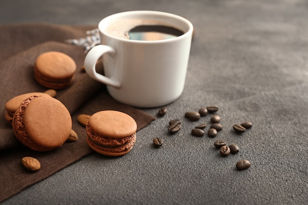 Smakelijke macarons met kopje koffie op grijze tafel