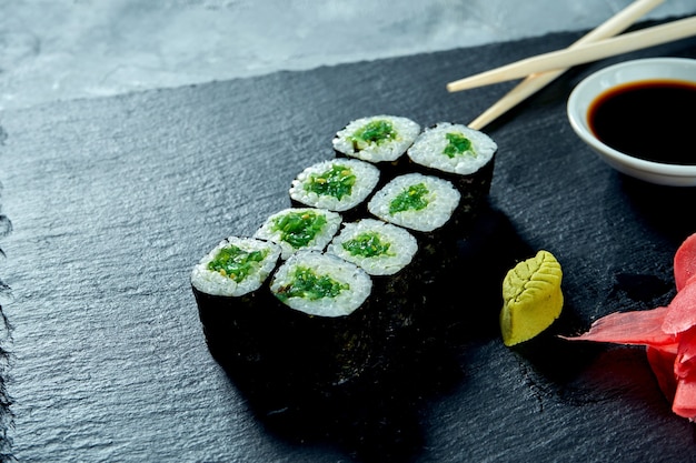 Smakelijke maki sushi met zeewier op een zwarte leisteen bord