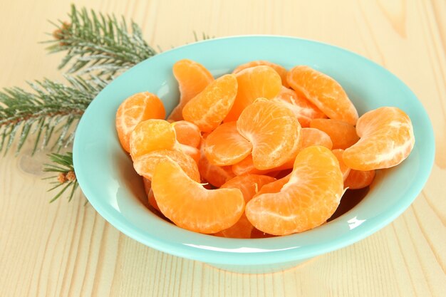 Smakelijke mandarijnenplakken in kleurenkom op lichte achtergrond