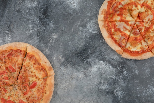 Smakelijke margherita en pittige kippenpizza op steenachtergrond.