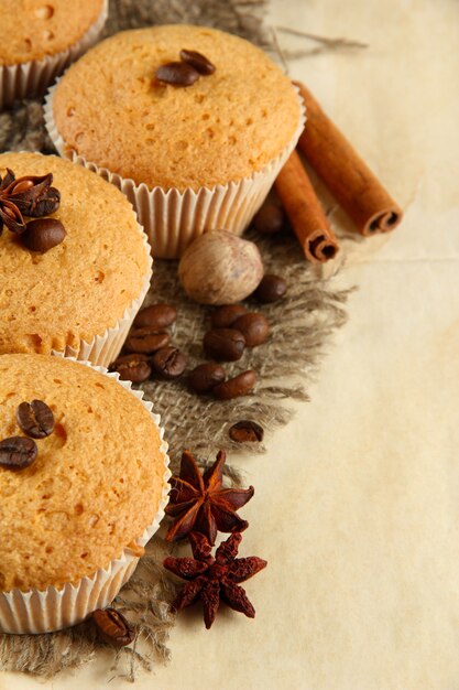 Smakelijke muffincakes op jute, kruiden en koffiezaden, op beige background