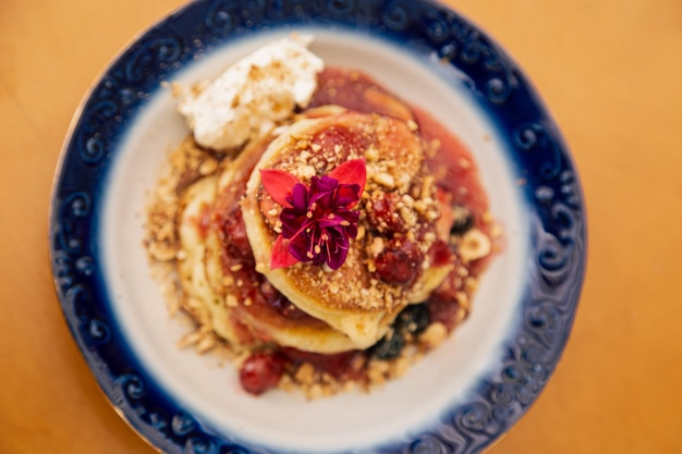 Smakelijke pannenkoeken versierd met bessen en bloemen