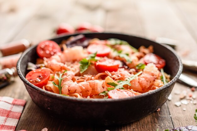 Smakelijke pasta met garnalen en tomaat op een koekenpan