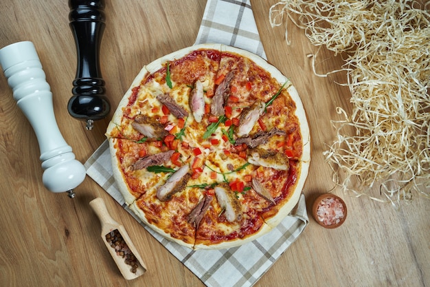 Smakelijke pizza met gesmolten kaas, varkensvlees, tomaten op een houten dienblad in een compositie met ingrediënten. Bovenaanzicht. Plat eten