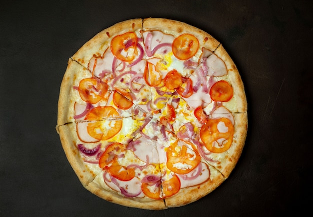 smakelijke pizza met ham, tomaat, Spaanse peper, tomatensaus, mozzarella kaas op een stenen achtergrond