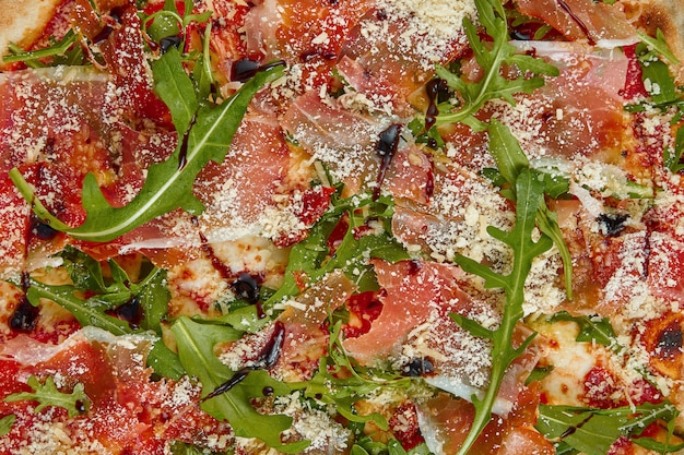 Foto smakelijke pizza met prosciutto di parma, rucola en parmezaanse kaas op een witte tafel. italiaanse traditionele keuken. heerlijk eten plat liggen. bovenaanzicht. textuur voor 3d