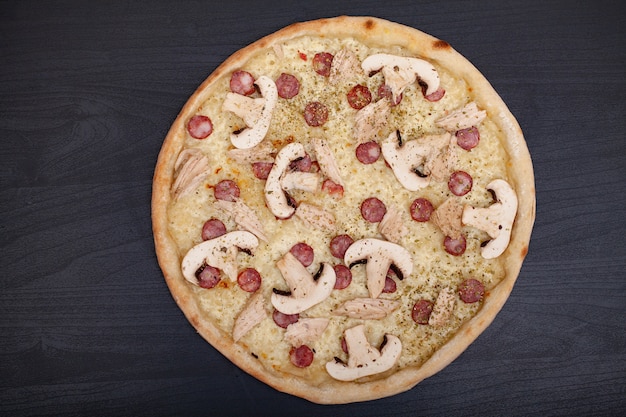 Smakelijke pizza met verschillende gearomatiseerde ingrediënten op donker