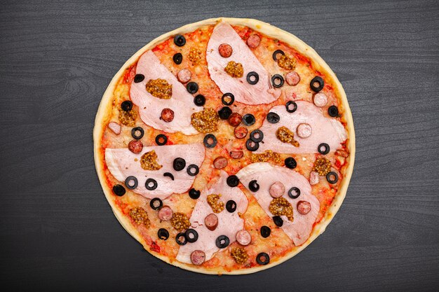 Smakelijke pizza met verschillende gearomatiseerde ingrediënten op donker