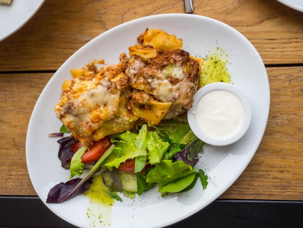 Smakelijke portie traditionele Italiaanse lasagne met gekruid rundergehakt op basis van tomaten en gesmolten mozzarella tussen lagen noedels met room en groene blaadjes