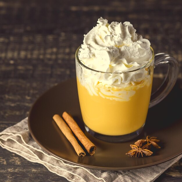 Smakelijke Pumpkin Latte met kruiden Slagroom bovenop op een donkere houten achtergrond Herfst warme drank