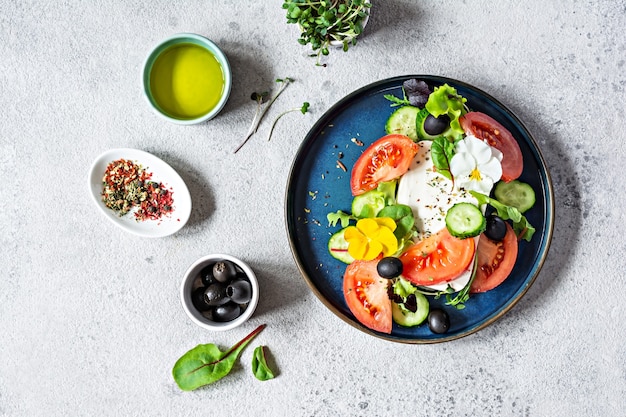 Smakelijke salade met fetakaas verse groenten tomaten komkommers uien krokante sla microgreens en violette bloemen Niet-standaard portie Griekse salade Eten met bloemen