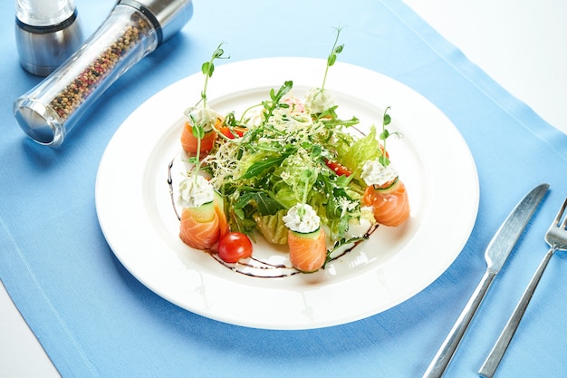 Smakelijke salade met zeevruchten, zalm, rucola en kerstomaatjes in een witte plaat op een blauw tafelkleed