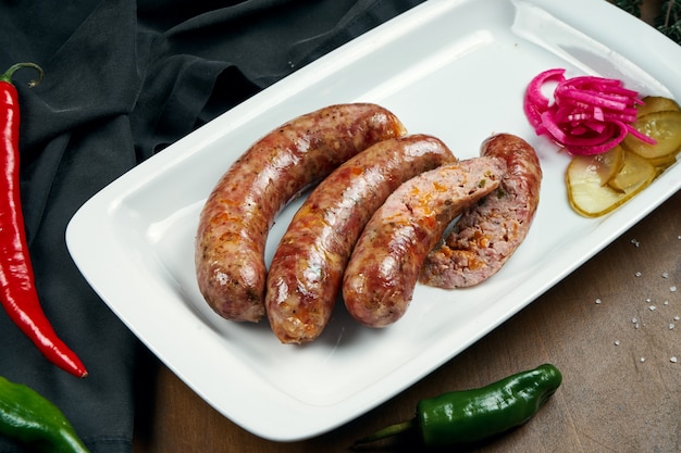 Smakelijke sappige varkensgehaktworst gegrild in een roker met cheddar in een witte plaat met ingeblikte groenten. Duitse biersnack