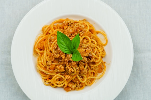 Smakelijke smakelijke klassieke Italiaanse spaghettideegwaren met tomatensaus en basilicum op plaat