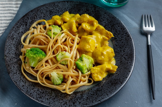 Smakelijke smakelijke noedels spaghetti udon met stukjes kip in kerriesaus geserveerd op plaat. Detailopname.