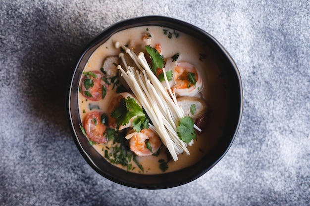 Smakelijke tom yam met enoki-paddenstoelen op een gestructureerde achtergrond