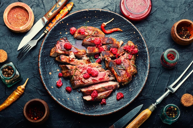 Smakelijke varkenssteak op een bord en frambozensaus