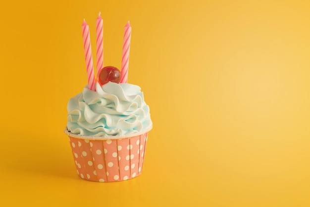 Smakelijke verjaardag cupcake met kaarsen op gele kleurenachtergrond