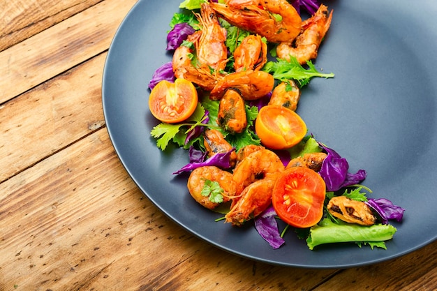 Smakelijke verse salade met garnalen, tomaat en sla op een bord.