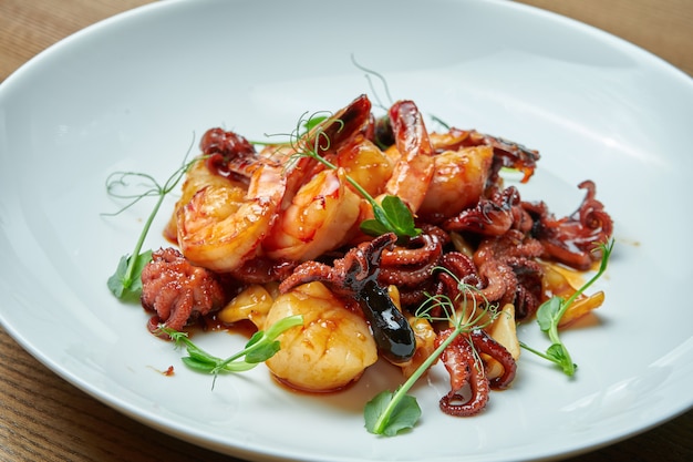 Smakelijke zeevruchtensalade in zoetzure saus in een witte plaat. Garnalen, octopus, sint-jakobsschelpen en inktvissalade