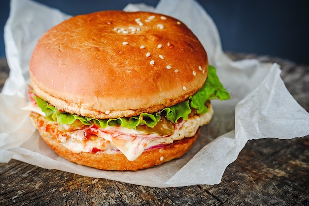 Smakelijke zelfgemaakte hamburger in inpakpapier op houten tafel