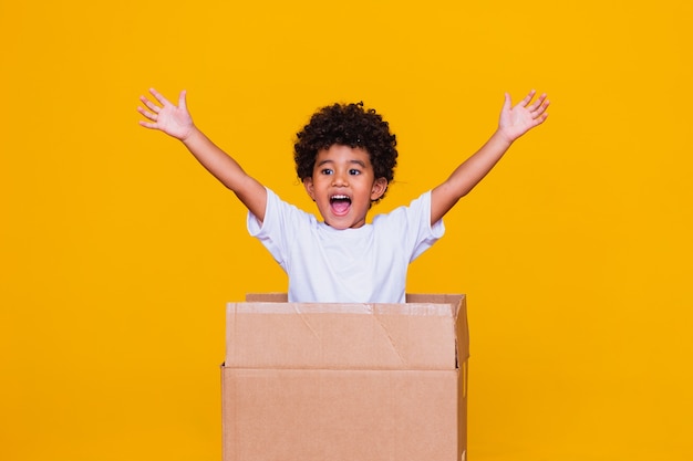 Small afro boy coming out of cardboard box.