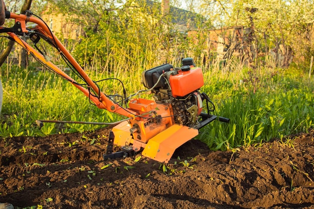 A small agricultural tractor plows the ground the work of a walkbehind tractor land treatment for planting