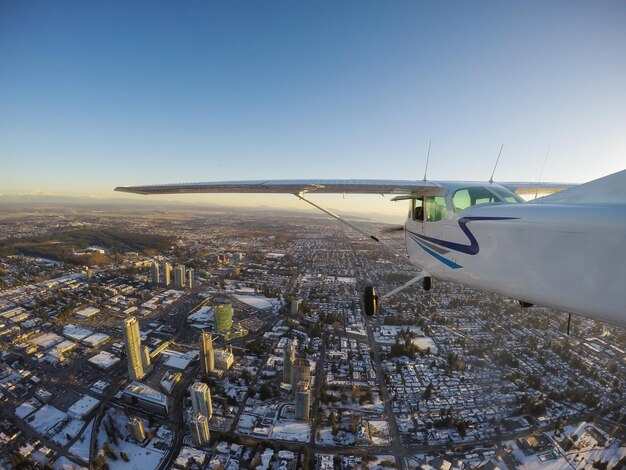 활기찬 겨울 일몰 동안 도시를 비행하는 소형 비행기