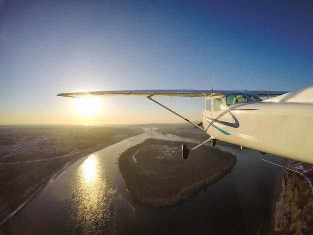 鮮やかな冬の日没時にフレーザー川上空を飛ぶ小さな飛行機