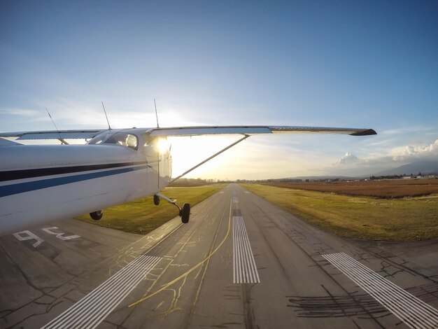 Небольшой самолет взлетает с взлетно-посадочной полосы во время яркого заката