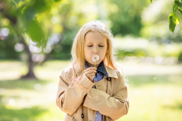 自然の中で彼女の手にタンポポの花で甘くて幸せな小さくて美しい女児