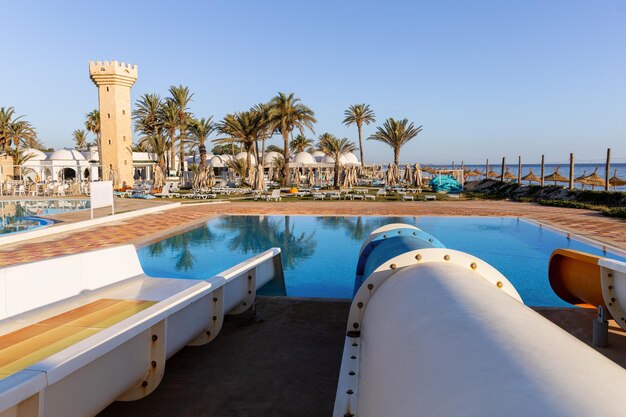 Фото Маленький аквапарк с бассейном и пальмами утром в тунисе