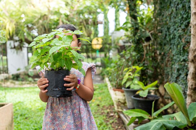 정원에서 houseplant를 들고 작은 아시아 소녀