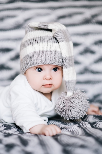 Photo small baby boy lying on stomach and raising his head awhile looking surprised and smiling cute, newborn