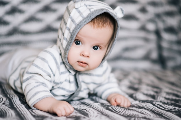 Small baby boy lying on stomach and raising his head awhile looking surprised and smiling cute, newborn