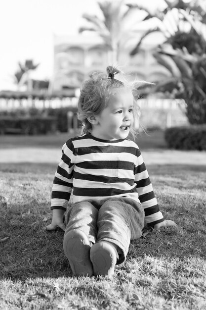 Small baby boy with happy face on green grass barefoot