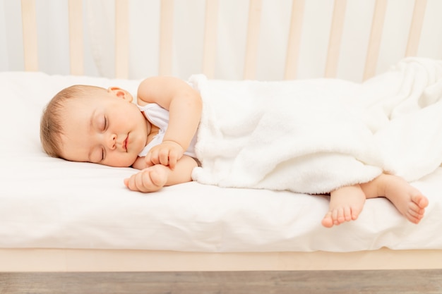 Photo small baby girl 6 months old sleeping in a white bed, healthy baby sleep