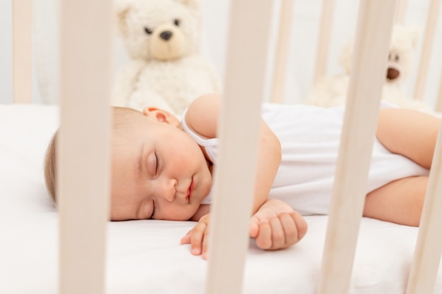 Small baby girl 6 months old sleeping in a white bed, healthy baby sleep